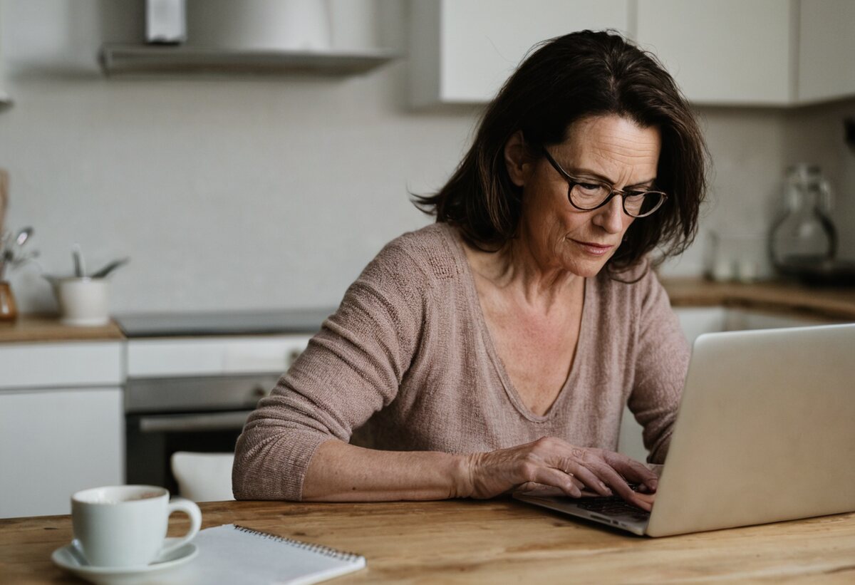 Illustrative photograph of a mature woman studying online at home
